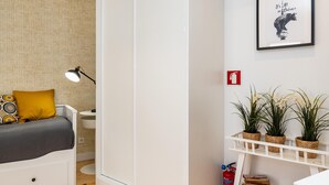A bedroom with a bed, bedside table, lamp, and a wall-mounted shelf with plants. - Belem Design Studio 2 by Homing (Lisbon)