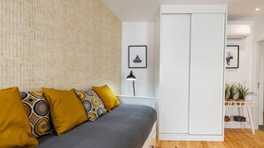 A modern bedroom with a bed, patterned pillows, a bedside table with a lamp, and a wardrobe. - Belem Design Studio 2 by Homing (Lisbon)