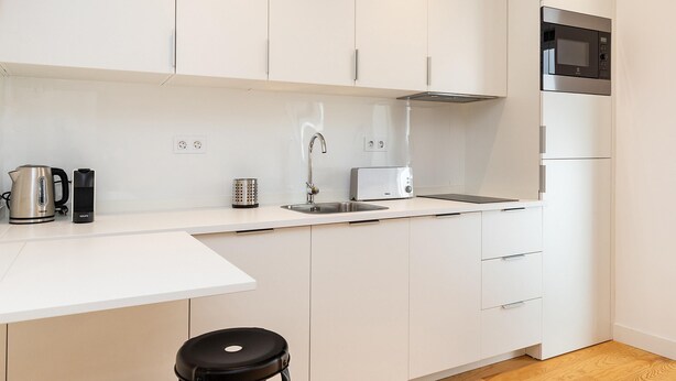 A modern kitchen with white cabinets, a stainless steel sink, a kettle, a toaster, and a microwave. - Belem Design Studio 2 by Homing (Lisbon)