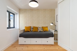 Ein Schlafzimmer mit Bett, Schreibtisch, Lampe und einem Fenster mit Blick.