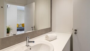 A modern bathroom with a large mirror, a white sink, and a towel on the counter. - Belem Design Studio 2 by Homing (Lisbon)
