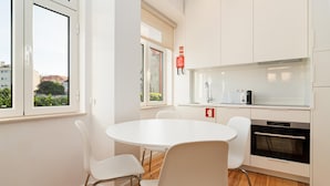 Una cocina moderna con armarios blancos, una mesa redonda y sillas blancas.
