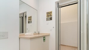 Un baño moderno con un espejo grande, un lavabo y una zona de ducha.