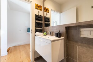 A modern bathroom with a white vanity, a large mirror, and a tiled shower area. - Belem Design 12 by Homing (Lisbon)