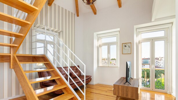 Un intérieur moderne avec un escalier en bois, un canapé en cuir, une table basse en bois et un téléviseur.