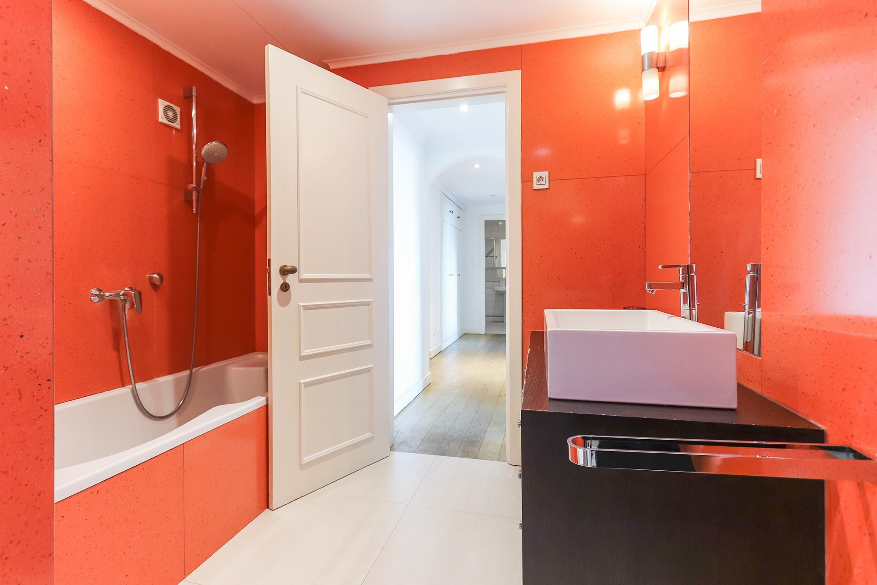 Une salle de bain moderne avec une baignoire blanche, une douche et un lavabo doté d’un plan de travail noir.