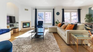 Un salon moderne avec un canapé, une table basse, un téléviseur et une cheminée.