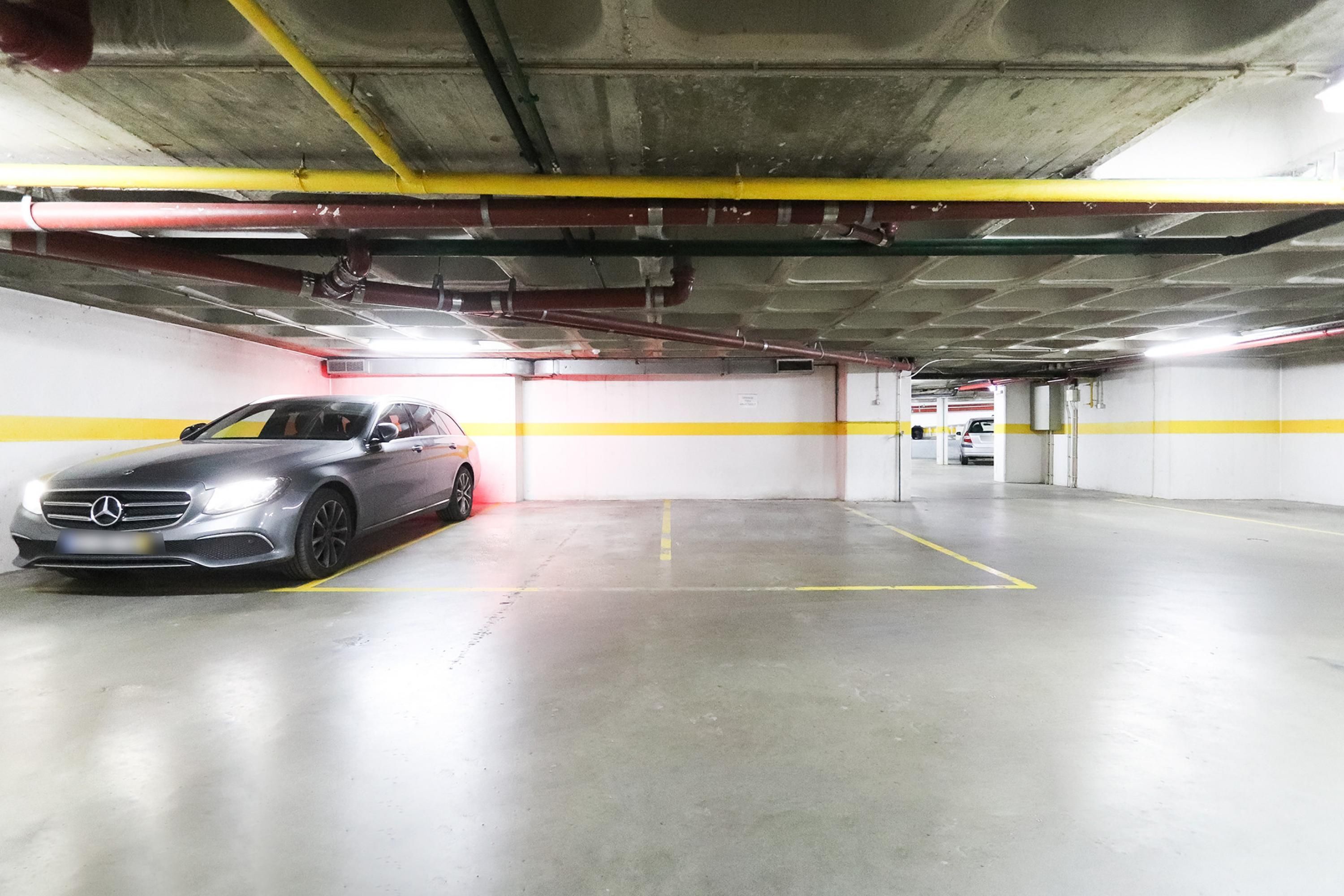 Un parking avec une voiture stationnée dans un espace réservé à cet effet.