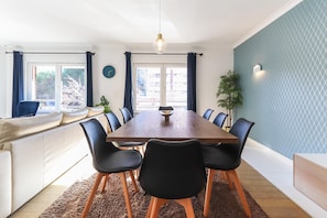 En matplats med ett träbord, svarta stolar, en vit soffa och en blå vägg med mönster.