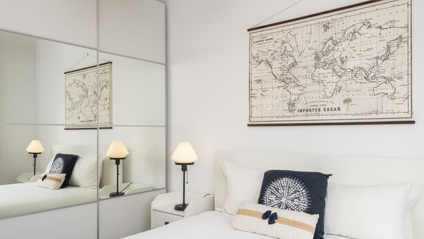Habitación de hotel con una cama grande, una mesita de noche, un espejo y un mapa colgado en la pared.