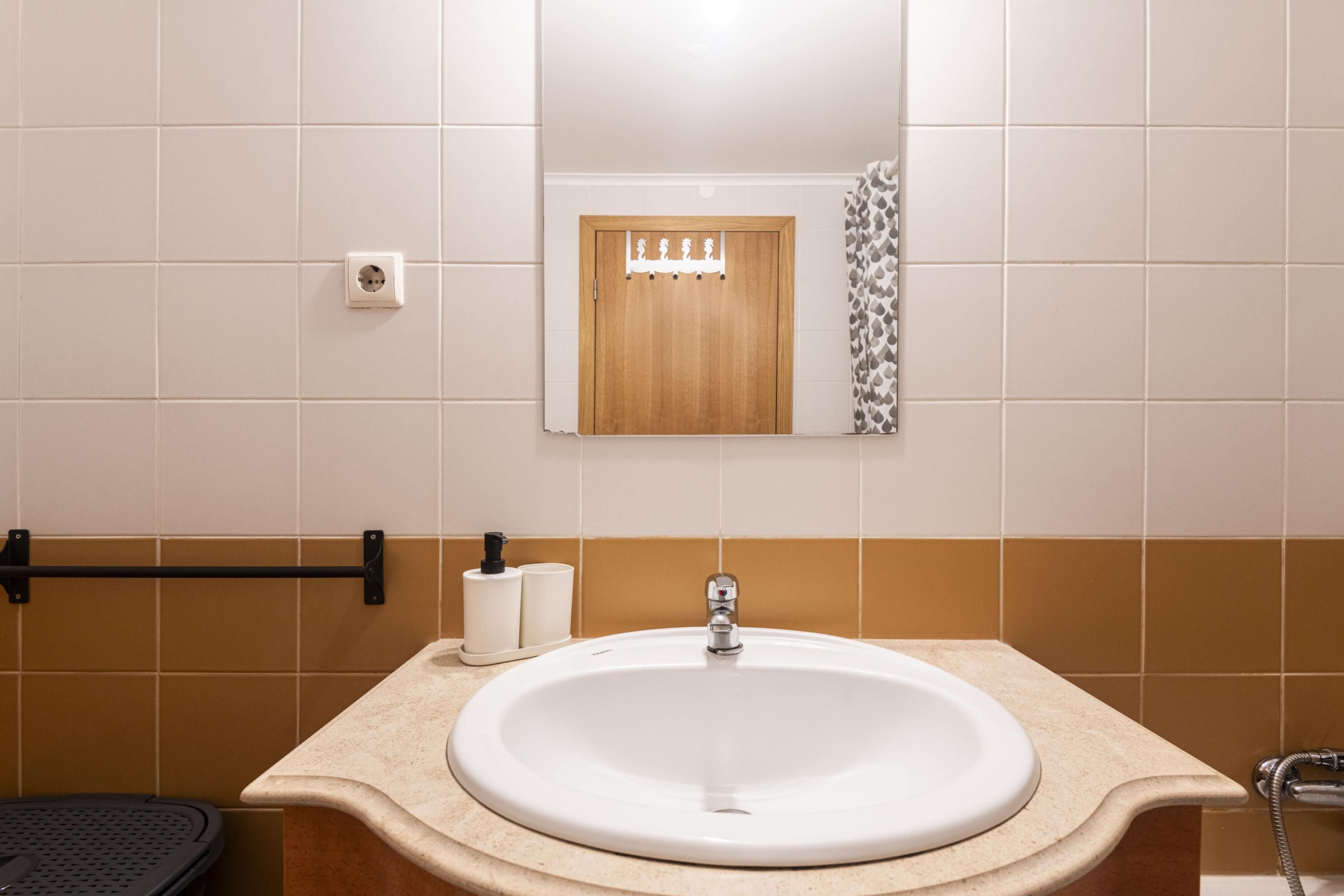 A bathroom with a white sink, a wooden door, a towel rack, and a toilet.