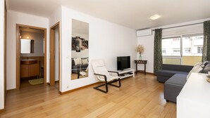 Una sala de estar moderna con un sofá, un televisor y un espejo que refleja la habitación.