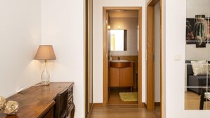 Un pasillo que conduce a un baño con un armario de madera y un lavabo.