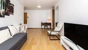 Una sala de estar con un sofá, una televisión, una mesa de comedor con sillas y una lámpara.