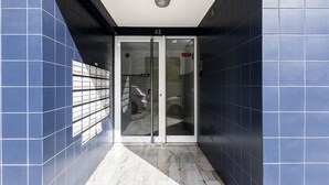 Un pasillo con paredes de azulejos azules y suelo de mármol que conduce a una puerta de cristal con el número 48.