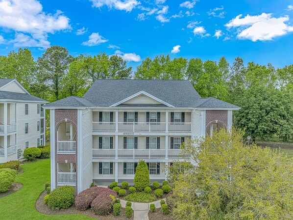 A two-story building with a balcony on the second floor, surrounded by well-maintained landscaping. - BEAUTIFUL FAIRWAYS (Myrtle Beach)