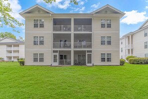 A multi-story residential building with a central entrance, balconies on each floor, and a well-maintained lawn. - BEAUTIFUL FAIRWAYS (Myrtle Beach)