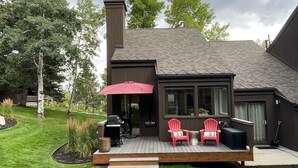 A modern house with a deck, a chimney, and a large window overlooking the yard. - Cozy Townhome next to PC Resort! Stylish 2BR/2BA +loft, deck, +more (Park City)
