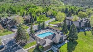 A residential area with houses, a swimming pool, and a hilly landscape in the background. - Cozy Townhome next to PC Resort! Stylish 2BR/2BA +loft, deck, +more (Park City)