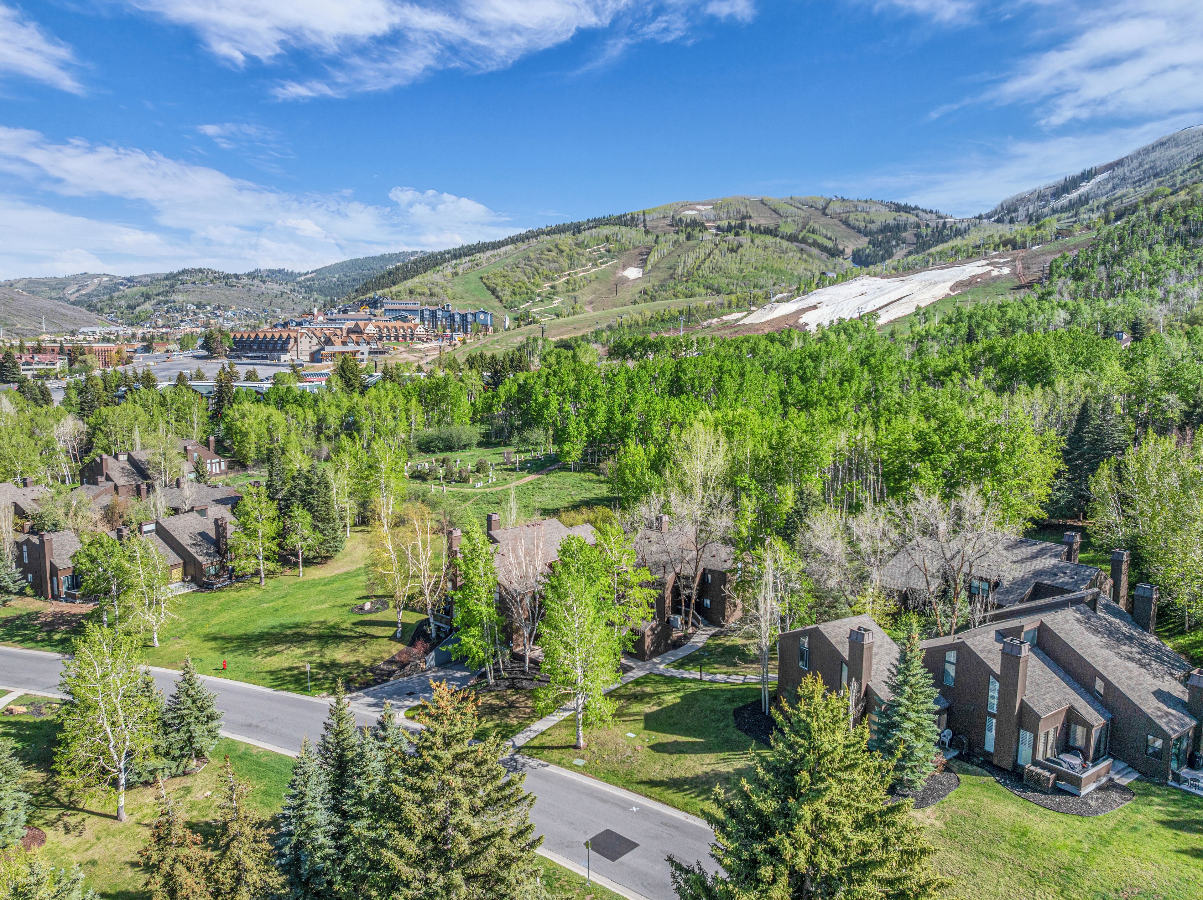 A residential area with houses, a road, and a hilly landscape in the background.