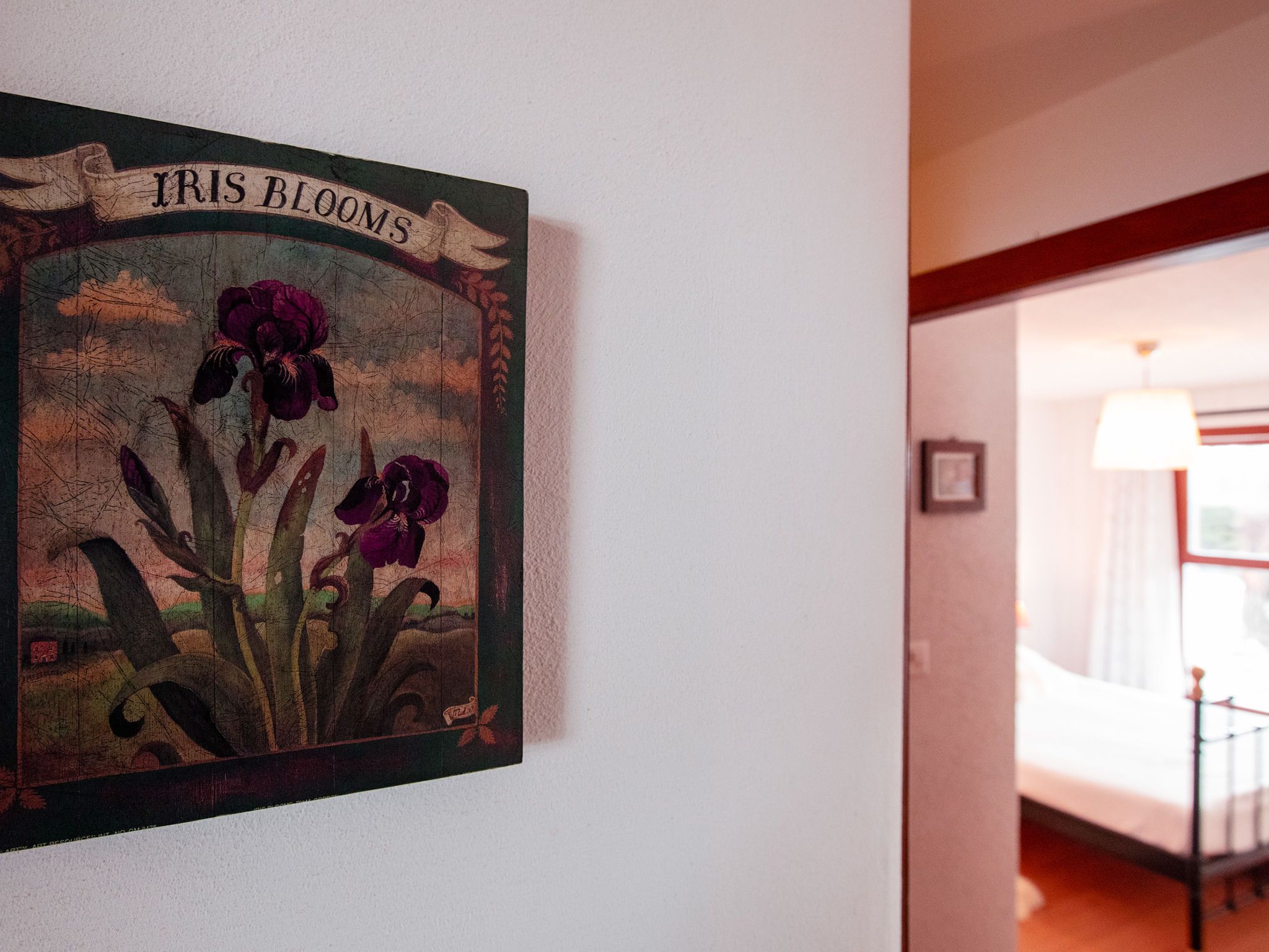 Una pared con un cuadro de flores de lirio y un letrero que dice 'IRIS BLOOMS'.