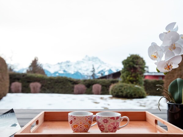 A wooden tray with two patterned cups and a potted orchid.