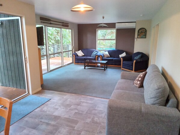 A spacious living room with a large window, a sofa, a coffee table, and a dining area.