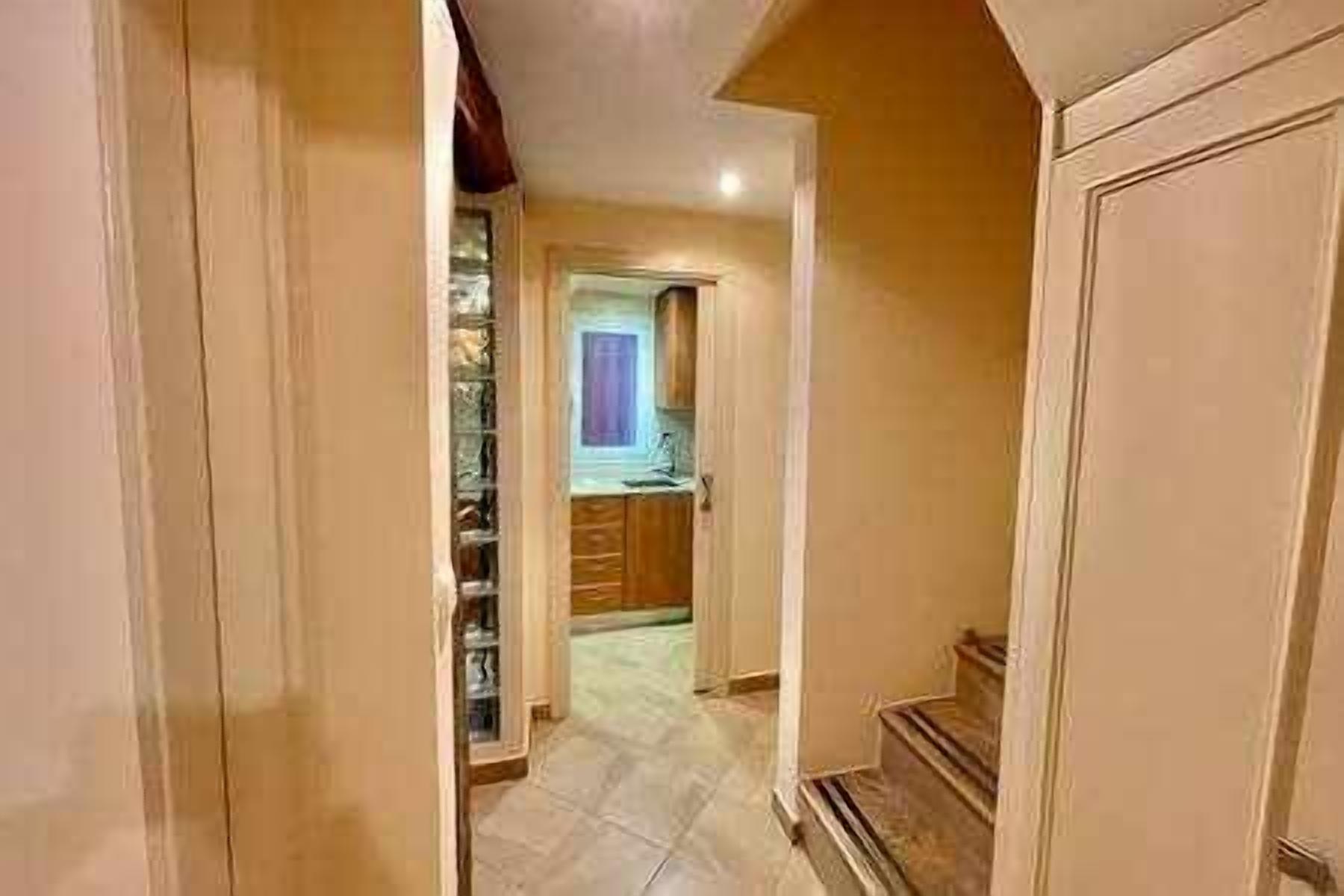Un pasillo que conduce a una cocina con armarios de madera y piso de baldosas.