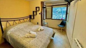 A bedroom with a bed, a chair, a window with a view, and a radiator. - Kai Etxea , el mismo puerto de Bermeo (Bermeo)