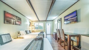 A hotel room with a large bed, a desk, a chair, a television, and artwork on the walls. - ORBOST MOTEL (Orbost)