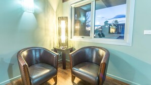 Two leather armchairs in a room with wooden flooring, a small table, and a window with a view of the outside. - ORBOST MOTEL (Orbost)