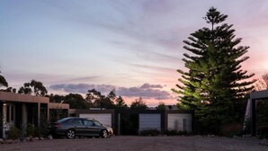 A modern building with a car parked in front, surrounded by trees and a clear sky. - ORBOST MOTEL (Orbost)