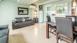 A living room with a sofa, a dining table with chairs, a refrigerator, and a window. - ORBOST MOTEL (Orbost)