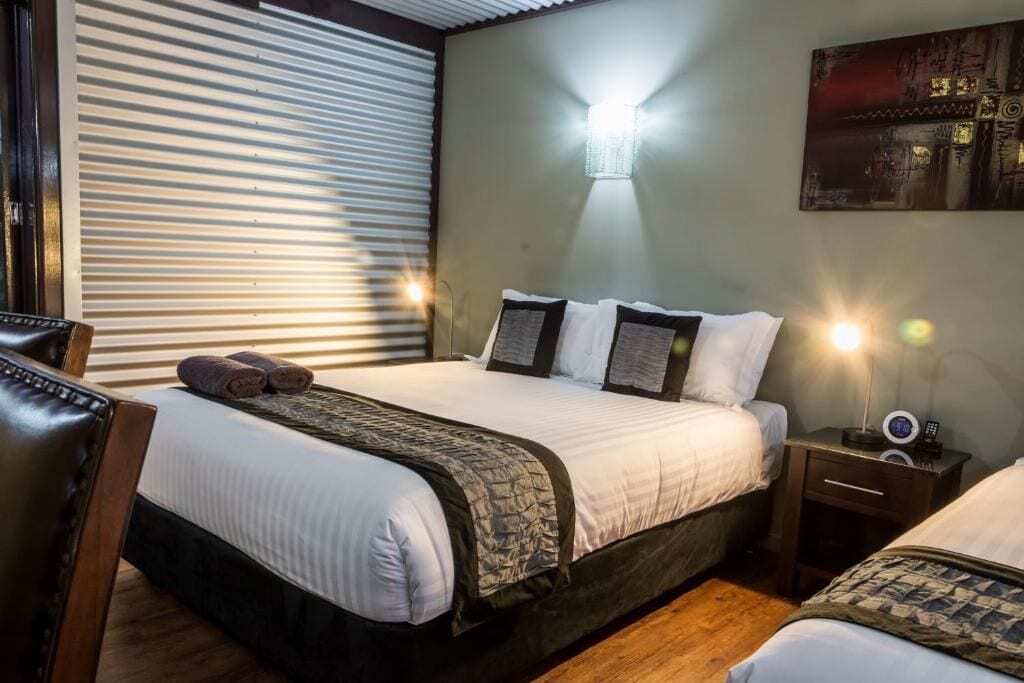 A hotel room with a bed, bedside tables, a lamp, and a painting on the wall.