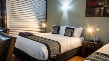 A hotel room with a bed, bedside tables, a lamp, and a painting on the wall.