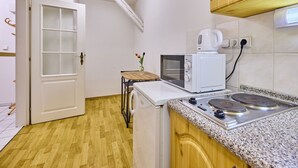 A compact kitchen with a microwave, kettle, and stove.