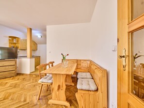 Une cuisine compacte avec des meubles en bois, une table à manger avec des bancs et un téléviseur.