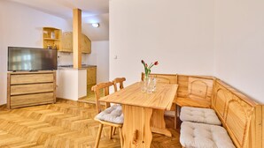Un espace de vie compact comprenant une table à manger en bois, un canapé et un téléviseur, le tout aménagé dans un coin cuisine.