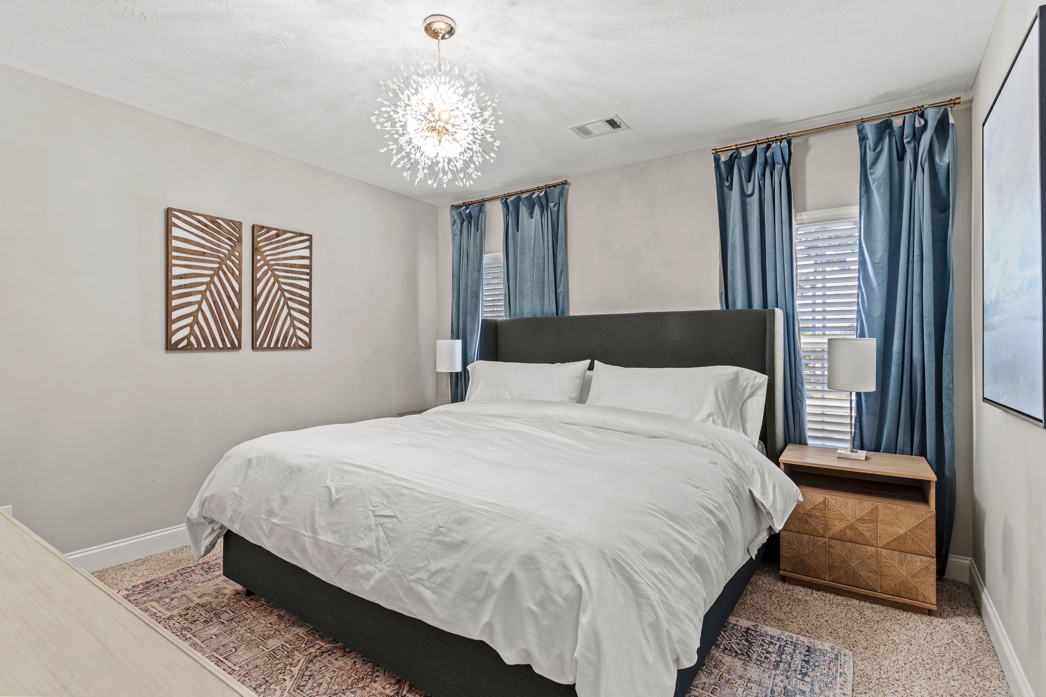 Une chambre à coucher avec un grand lit, une table de chevet, un élément décoratif mural et un lustre.