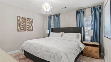 Une chambre à coucher avec un grand lit, une table de chevet, un élément décoratif mural et un lustre.