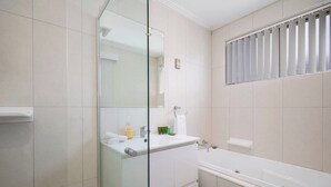 A modern bathroom with a glass shower enclosure, a white sink, and a bathtub. - Oceans at Terrigal, a Beachfront Oasis (Terrigal)
