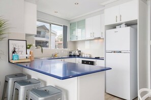 Une cuisine moderne avec des meubles blancs, un plan de travail bleu et un lave-vaisselle encastré.