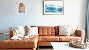 Un salon moderne avec un canapé en cuir marron, une table basse blanche et une lampe en osier.