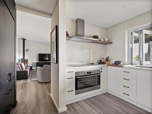 Une cuisine moderne avec des meubles blancs, un four encastré et une grande fenêtre.