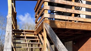 Una escalera de madera que lleva a una terraza con un muro de ladrillo al fondo.