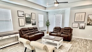 Ein geräumiges Wohnzimmer mit einem braunen Ledersofa, einem weißen Sessel und einem Couchtisch.