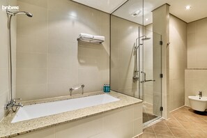 A modern bathroom with a large bathtub, a glass-enclosed shower, and a separate sink area. - 1B-AnantaraSouth-G02 by bnbmehomes (Dubai)