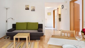 A living room with a sofa, a small table, a dining table with chairs, and a glass of water. - Apartment 'Ferienwohnung Glöckler' with Shared Garden and Wi-Fi (Freiburg im Breisgau)