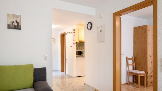 A living room with a sofa, a wooden door, and a view into the kitchen. - Apartment 'Ferienwohnung Glöckler' with Shared Garden and Wi-Fi (Freiburg im Breisgau)