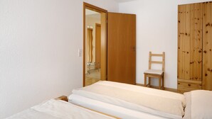 A bedroom with a bed, a wooden wardrobe, a chair, and a mirror. - Apartment 'Ferienwohnung Glöckler' with Shared Garden and Wi-Fi (Freiburg im Breisgau)